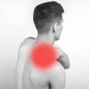 Black and white shot of man from behind who is experiencing neck pain. The area where he's experiencing pain has been highlighted red. in the image. 