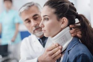 Professional doctor visiting a young injured patient at the hospital, he is adjusting her cervical collar