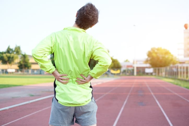 Runner on track grabs lower back in pain