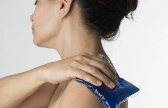Woman holding gel pack on shoulder.