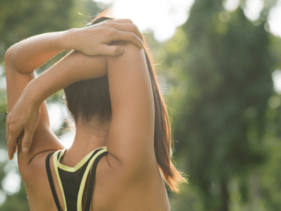 Rear view of woman stretching her arm and shoulder