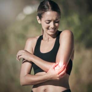 Woman athlete outside holding her elbow in pain due to elbow fracture