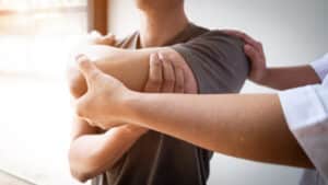 Medical professional helping patient stretch shoulder to evaluate rotator cuff